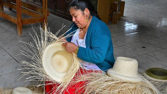 Una tejedora se afana con las hebras de paja toquilla para confeccionar un sombrero