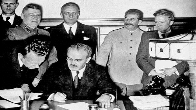 Mólotov firma el pacto de no agresión. Tiene detrás de él a Ribbentrop, que aparece acompañado de un sonriente Stalin (segundo por la derecha)