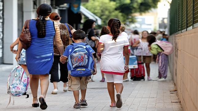 Imagen de dos niños yendo al colegio acompañados por su madre