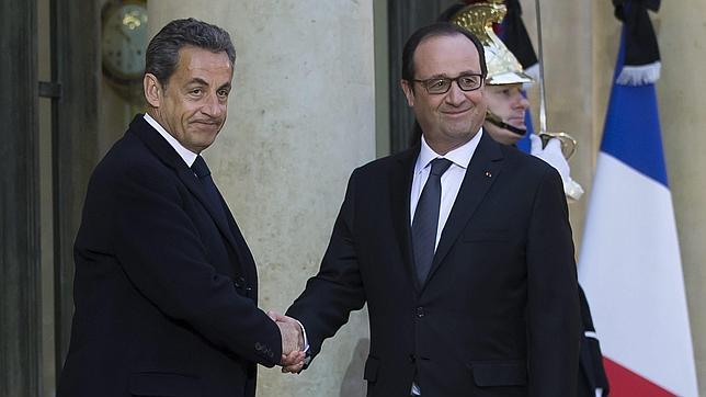 El presidente galo, François Hollande (dcha), estrecha la mano al expresidente francés y líder opositor Nicolas Sarkozy (izq), tras mantener una reunión en el Palacio del Elíseo en París (Francia)