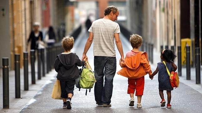 Un padre acompaña a sus pequeños al colegio