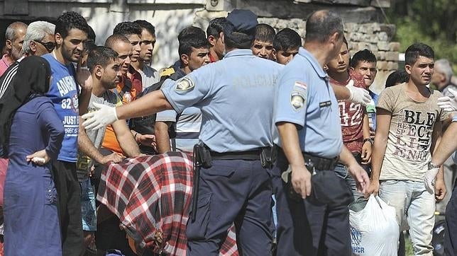 Policías croatas dirigen a varios refugiados a un autobús que les trasladará a un centro de acogida, tras cruzar la frontera con Serbia