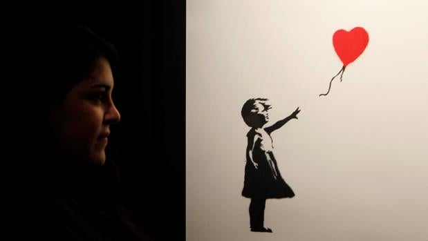 Una joven contempla «Niña con globo», una de las imágenes más icónicas de Banksy