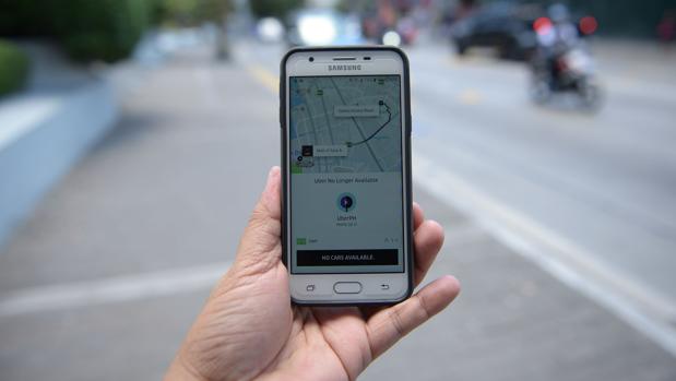Imagen de un hombre sujentando su teléfono con la aplicación de Uber