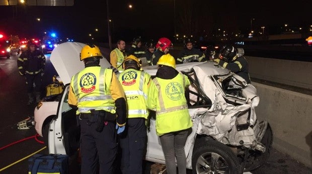 Los bomberos y efectivos de emergencias tratan de liberar del taxi al conductor y a la pasajera
