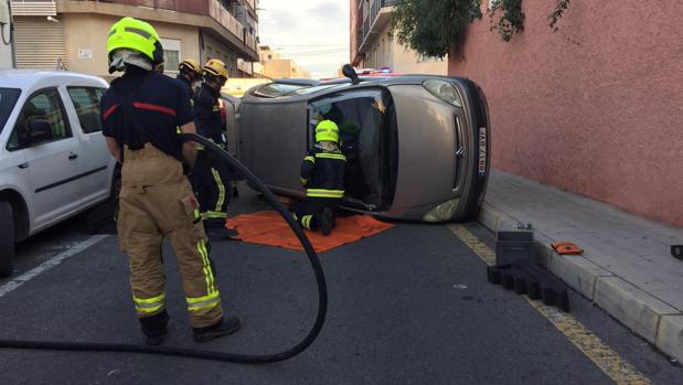 Bomberos excarcelando al conductor herido y atrapado en su coche tras volcar
