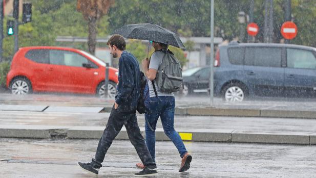 Dos jóvenes se protegen de la lluvia en los poblados marítimos de Valencia