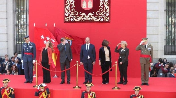 Las autoridades se protegen de las ventolera que provocó un helicóptero durante el desfile en la Puerta del Sol