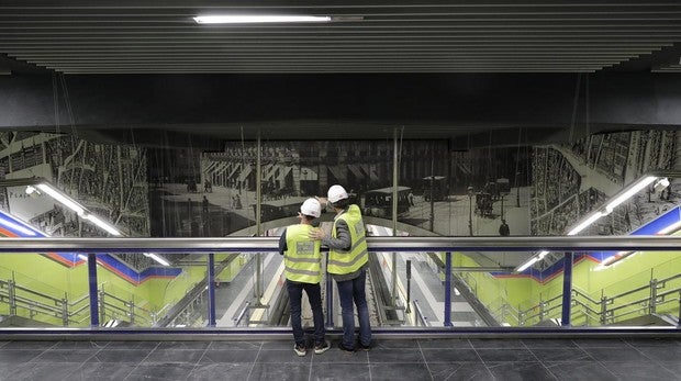 Dos obreros observan el gran mural que preside el andén central de la estación de Sevilla