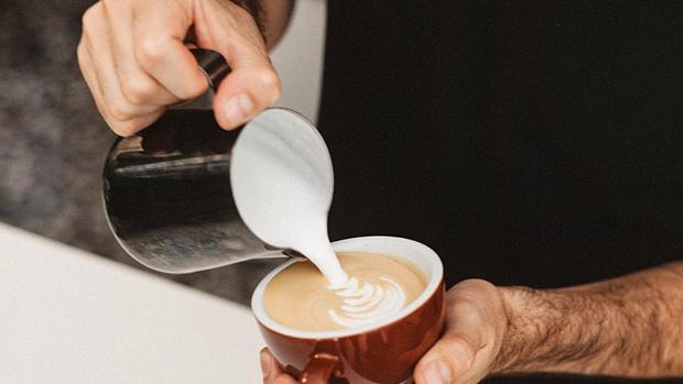 Un profesional sirviendo una taza de café con leche