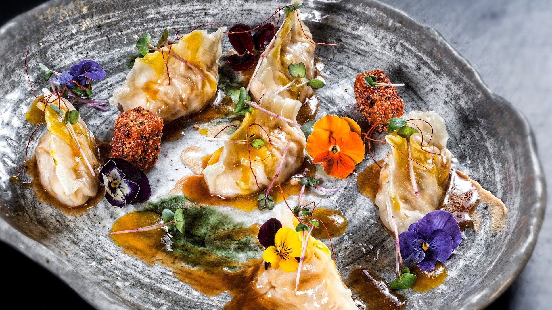 Gyozas de pollo de corral con glasé de azafrán, almendra tostada y gominola ácida de maracuyá.