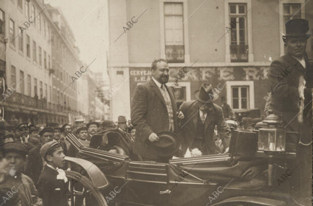 El eminente novelista, al salir de las estación, saludando a sus admiradores que...