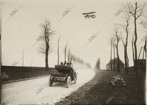 El aviador Henry Farman atravesando en su biplano, con un viajero, la carretera...