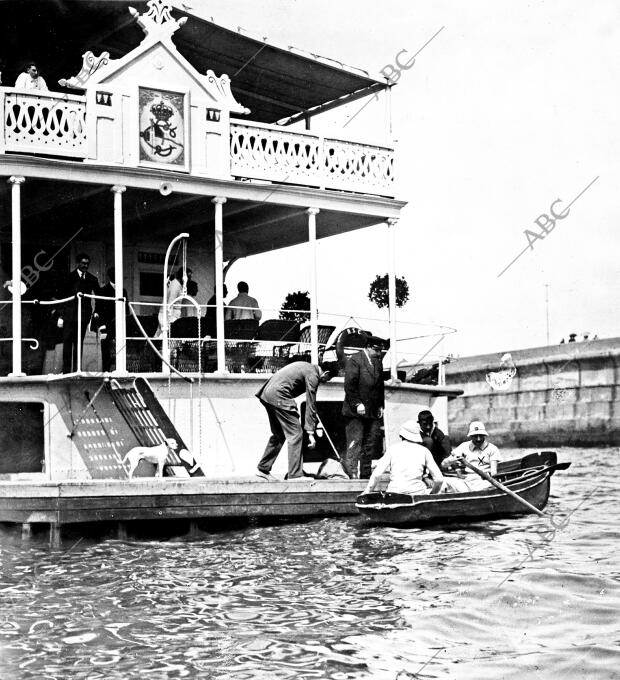 S.M. el Rey (X), Remando en un bote pequeño ante la plataforma del real Sporting...