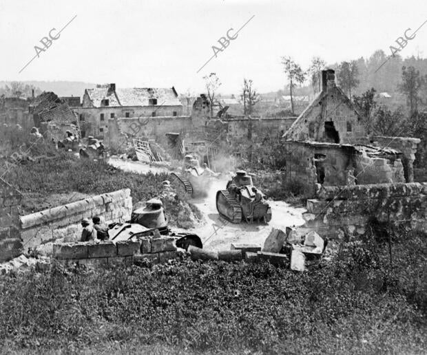 Carros de asalto de tipo moderno pasando por entre las ruinas de una aldea