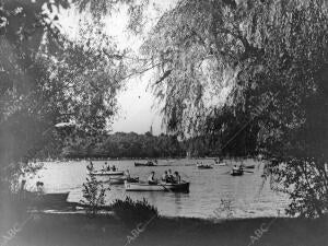 (Ca.) Vista del estanque del Parque del Retiro con personas en barcas, en los...