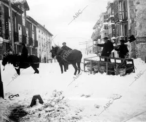Hombres trasportando carbón por la nieve por una de las calles de Reinosa