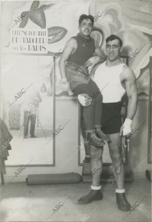 El boxeador Primo Carnera sostiene al campeón del mundo de pesos moscas, Young...