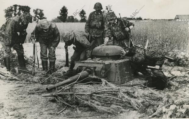 Soldados alemanes contemplan uno de tantos carros soviéticos enterrados en el...