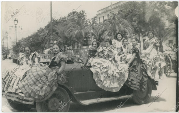 Un automóvil lleno de mujeres vestidas de flamenca las calles y el Real
