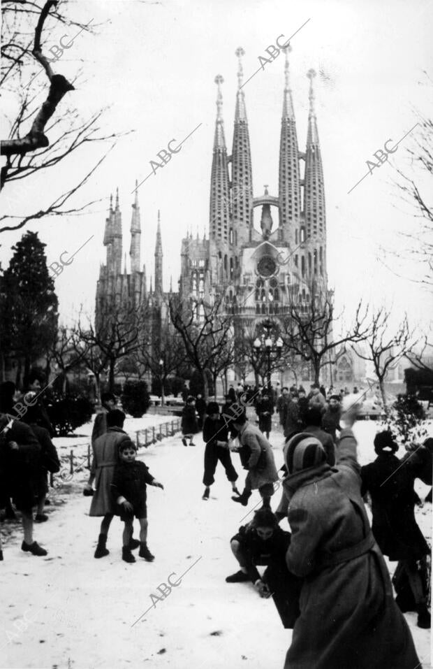 Unos niños juegan con la nieve frente a la Sagrada Familia