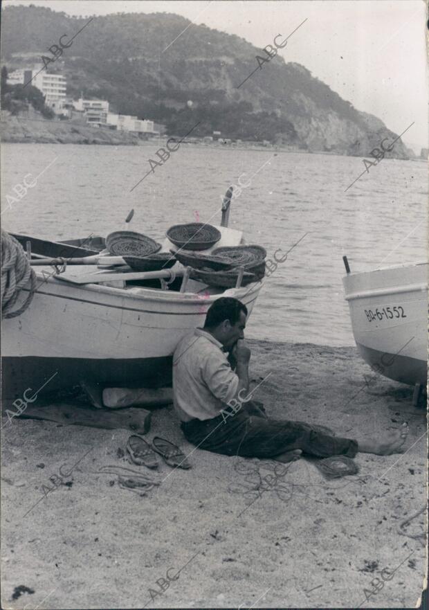 Un hombre al lado de una Barca en la playa de Tossa de mar