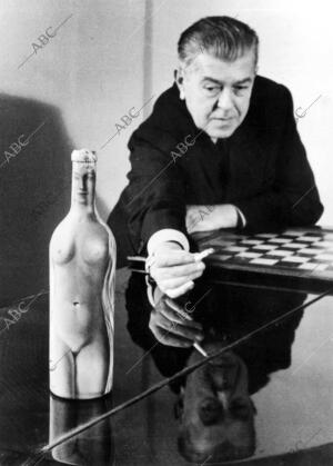 El pintor René Magritte junto a una botella pintada por él