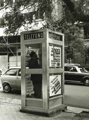 Señor habla por teléfono en una cabina con publicidad de Blanco y Negro