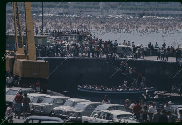 Gente en el puerto, llegando en barcas y bañándose en la Playa de la Concha, al...