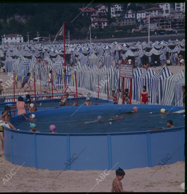 Niños dan clases de natación en una piscina desmontable puesta encima de la...