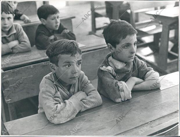 Dos niños atienden las explicaciones de su maestro, Don Esteban García, pariente...