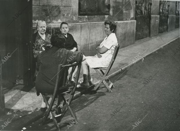 Unas mujeres pasan la noche sentadas en la calle al aire, para evitar el calor