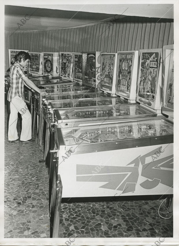 Un jóven jugando en un salón de juegos recreativos a una máquina de pinball