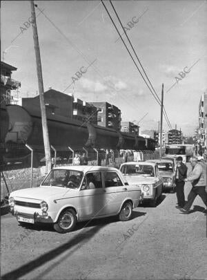 Fila de Automóviles junto A la vía del Tren, al cual se Puede apreciar tras las...