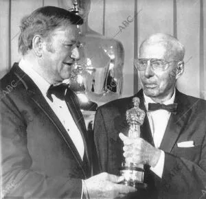 El actor John Wayne sostiene el Oscar con el director de cine Howard Hawks, que...