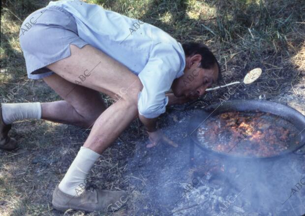 El novelista español Miguel Delibes, cocinando una paella en el campo durante...