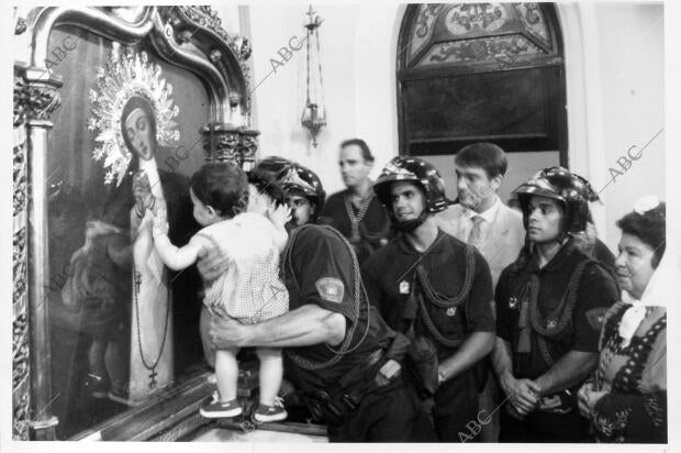 La Virgen de la Paloma recibe un beso de un niño de corta edad, al que sujeta...