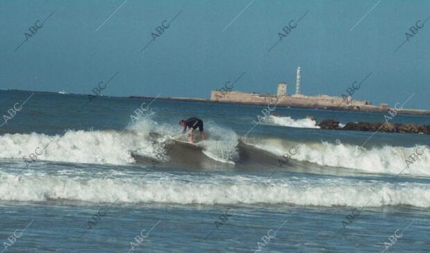 Un surfista sortea las olas en una playa de Cadiz a pesar de la sensible bajada...