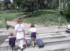 Niños Cruzan un paso de cebra con el uniforme del Colegioprimer semáforo con...