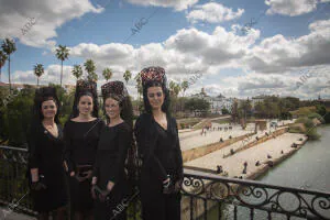 En la imagen, cuatro mujeres vestidas de mantilla en el puente de Triana