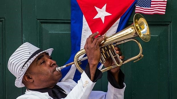 Un cubano toca la trompeta junto a una bandera de su país y otra de EE.UU., en La Habana
