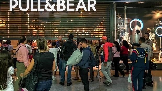 Un grupo de personas hace cola frente a una tienda en un centro comercial de Caracas