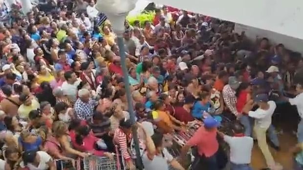 Carros de la compra intentan contener a la ingente cantidad de gente que lucha por llevarse algo a la boca