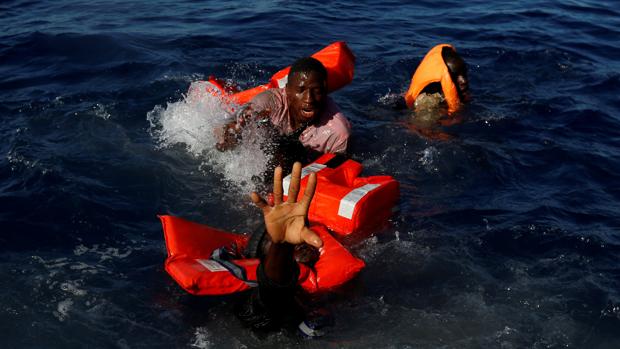 Tres tratan de mantenerse a flote tras el naufrafio de su embarcación en las costas de Libia, en 2017