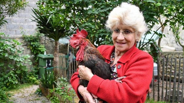 Corinne Fesseau posa con su gallo Mauriice en el jardín de su casa