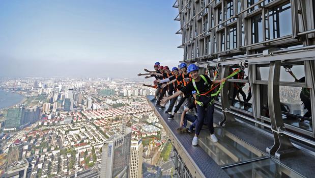 Un grupo de personas camina sobre una pasarela acristalada en el piso 88 de la Torre Jinmao en Shanghái (China)